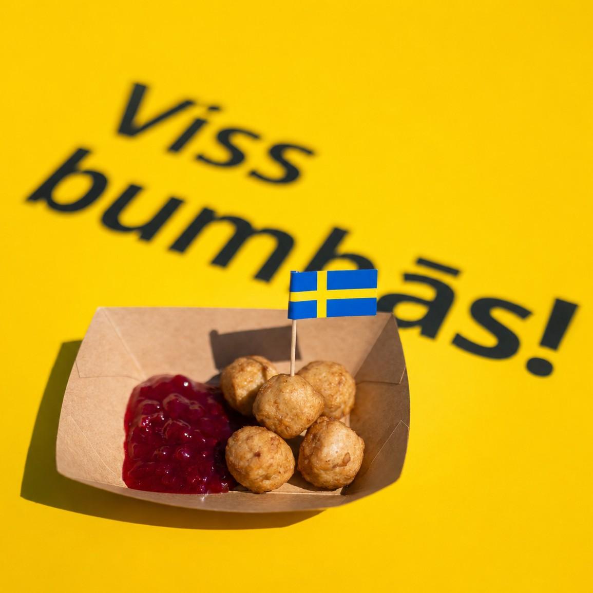 На жёлтом фоне написано «Viss bumbas», сверху — картонное блюдо с фрикадельками, брусничным соусом и шведским флагом.