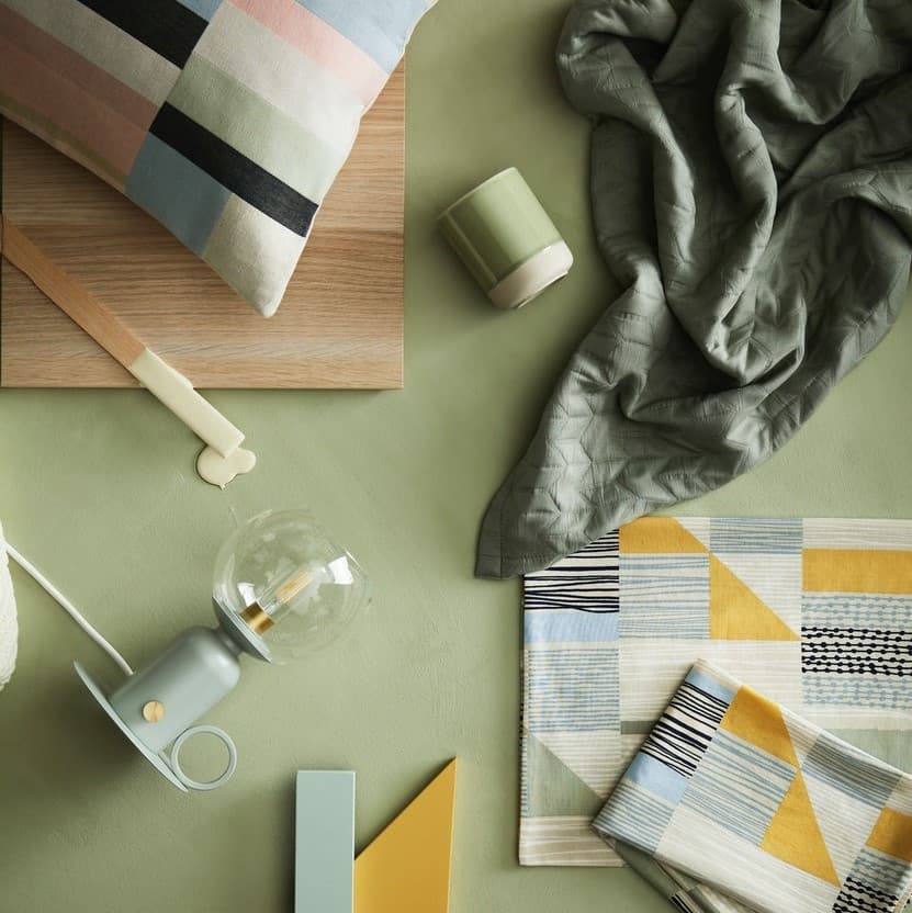 Na zielonym materiale leży zielona lampa oraz wzorzyste materiały.