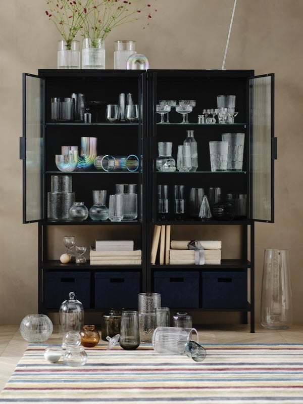 Na żółtym parapecie stoi niebieski wazon GRADVIS ze świeżymi kwiatami oraz jasnożółty wazon CHILIFRUKT.