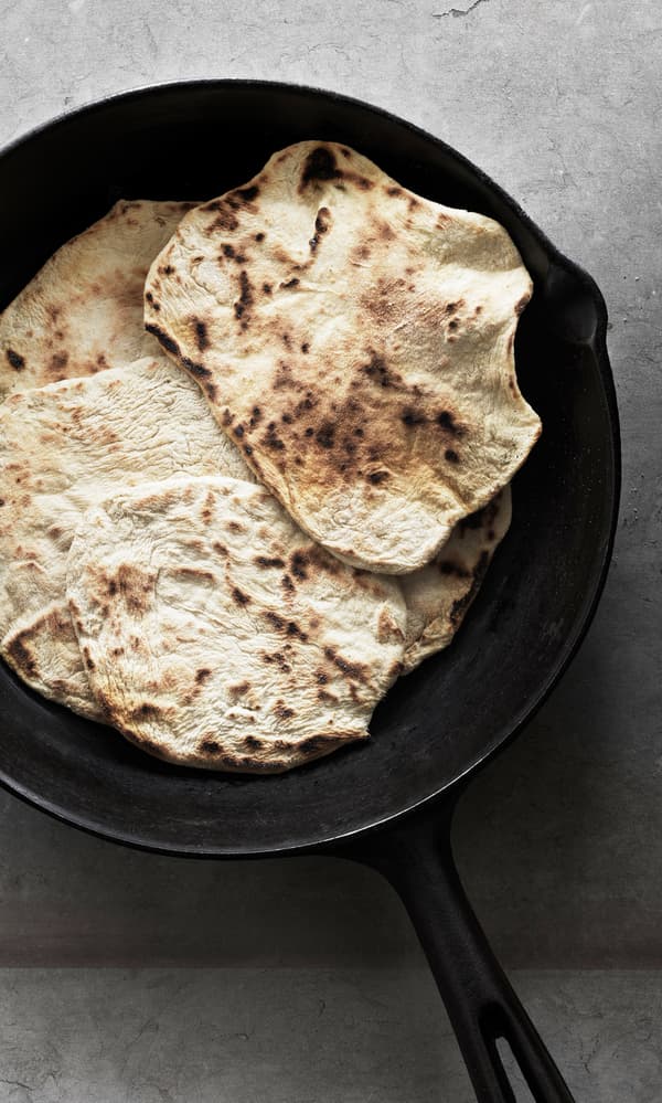 Naan bread served on a black plate, seen from above.