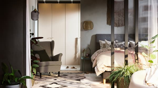 Nachhaltiges Schlafzimmer mit einer PAX/REINSVOLL Kleiderschrankkombination neben einem IDANÄS Bettgestell.