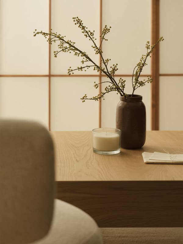 ナチュラルな配色の机の上に、ブラウンの花瓶と、透明なガラスに入ったキャンドル。