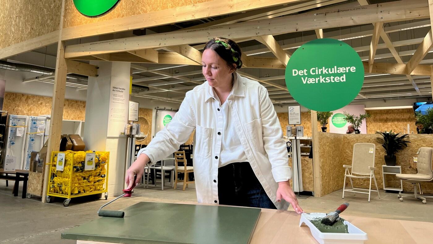 Nadia Zinck maler en køkkenlåge grøn foran Cirkulär i et IKEA varehus.