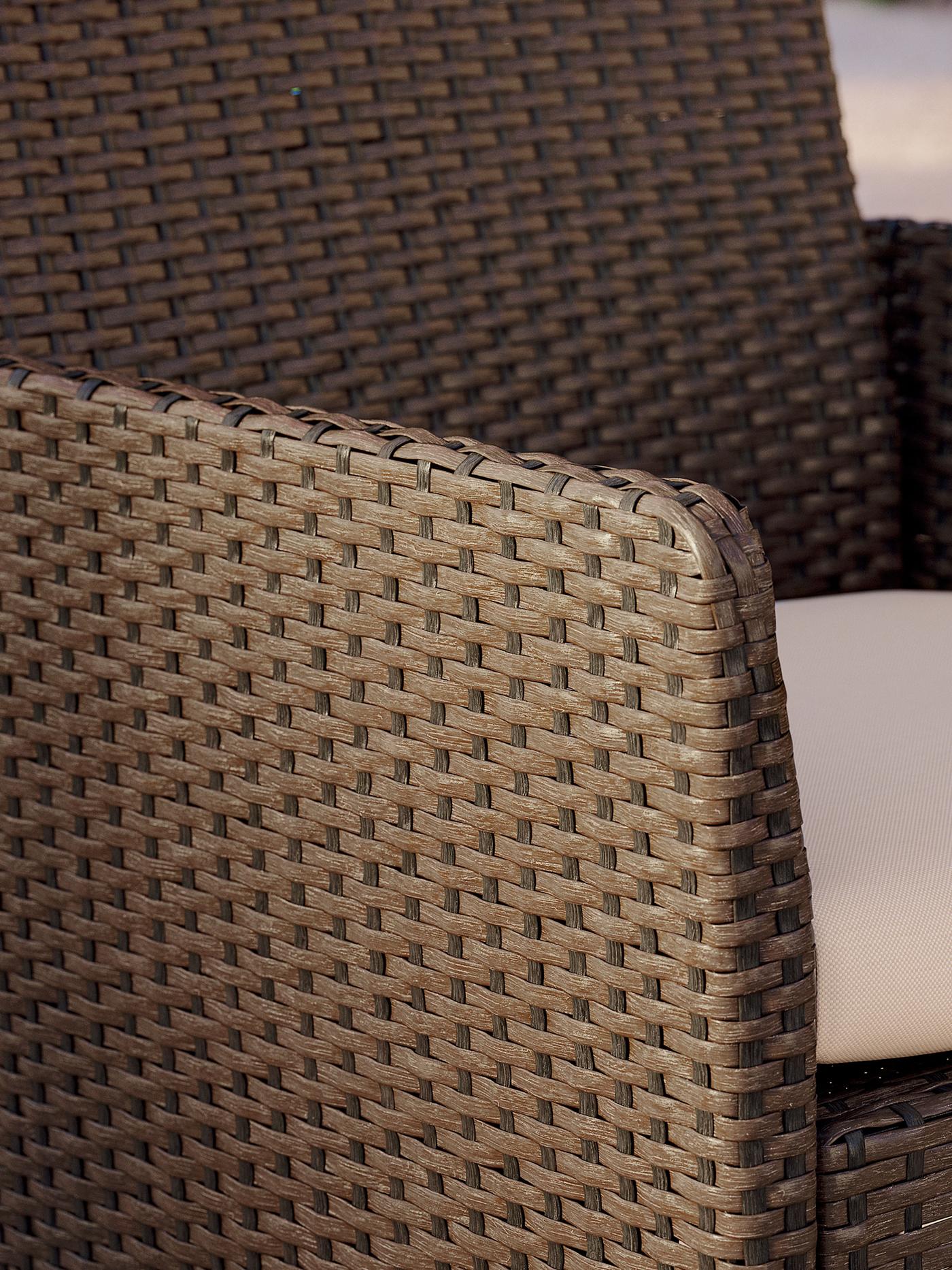 Närbild av en utomhusfåtölj i konstrotting med vävd struktur och ljus sittdyna.
