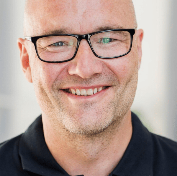 Närbild på en person med glasögon som ler mot kameran.