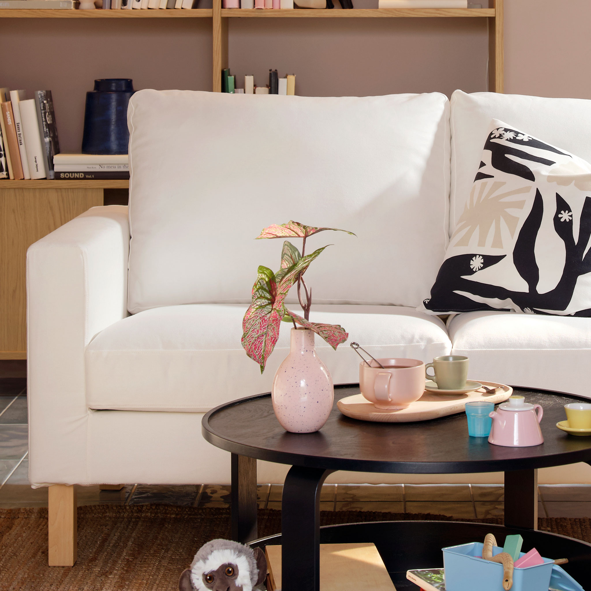 Närbild på en vit soffa med ljusa träben i ett vardagsrum. 