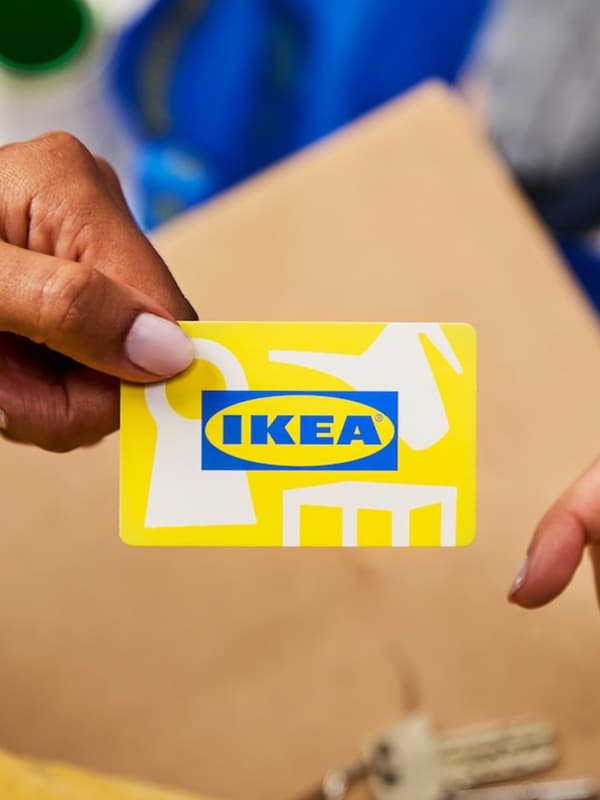 Närbild på ett IKEA presentkort som lämnas från en person till en annan.