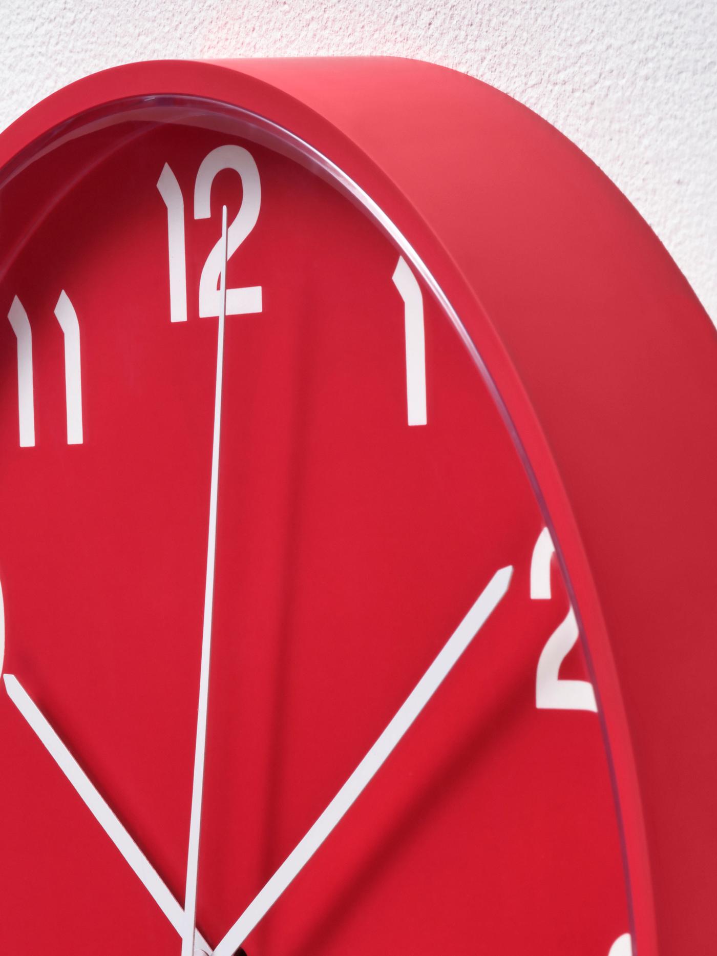 Närbild på röd väggklocka med vita siffror.