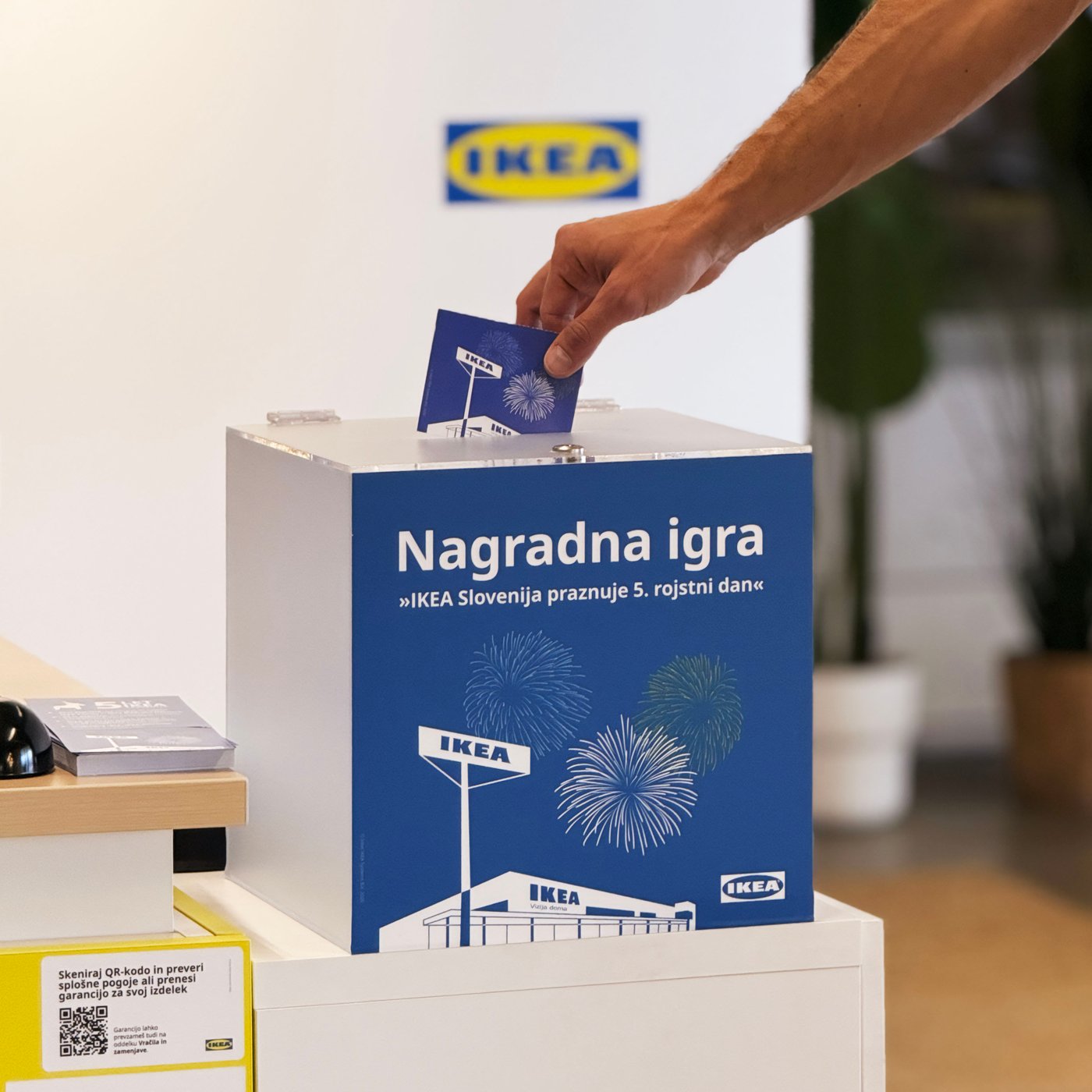 Nagradni boben za nagradno igro IKEA Slovenija praznuje 5 let in roka z nagradnim letakom.