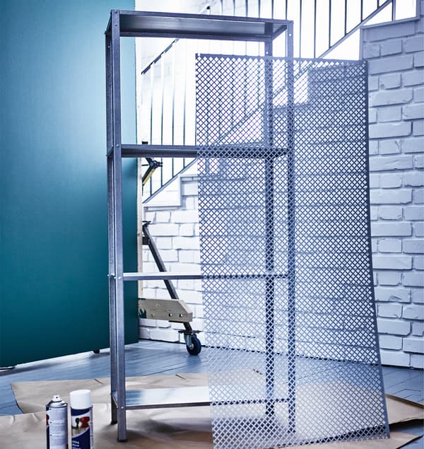 Nagy fémhálós lap, amely a festetlen IKEA polcnak van támasztva.