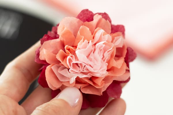 Nahaufnahme der Serviettenblume. Eine Hand hält sie in die Kamera. 