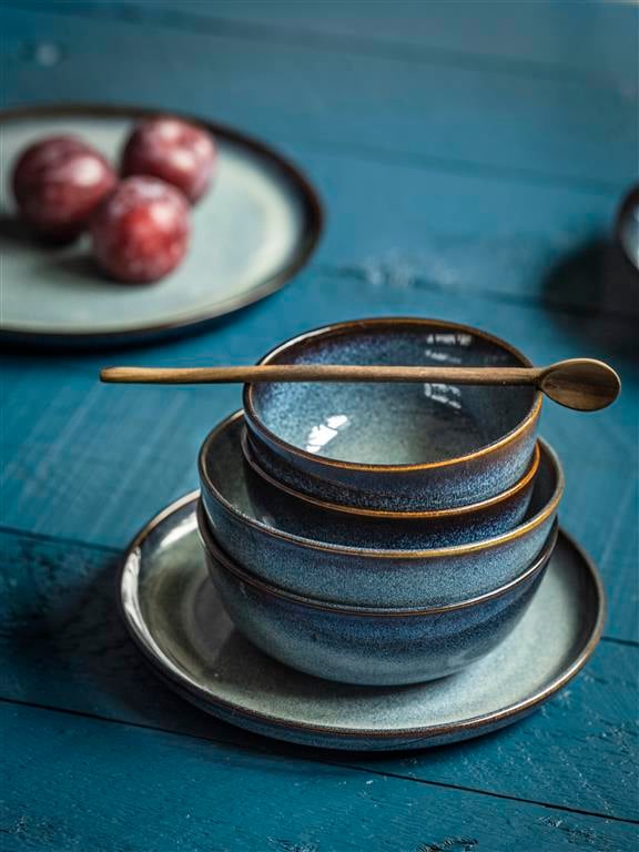 Nahaufnahme von einem Teller, auf dem verschiedene Schüssel gestapelt wurden. Auf der obersten liegt quer ein Holzlöffel