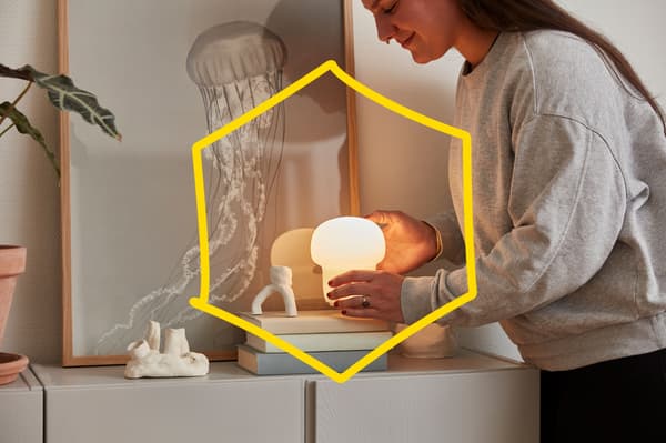 Nainen asettaa pientä pöytävalaisinta kirjapinon päälle.