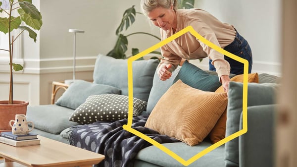 Nainen pöyhii sohvatyynyjä.