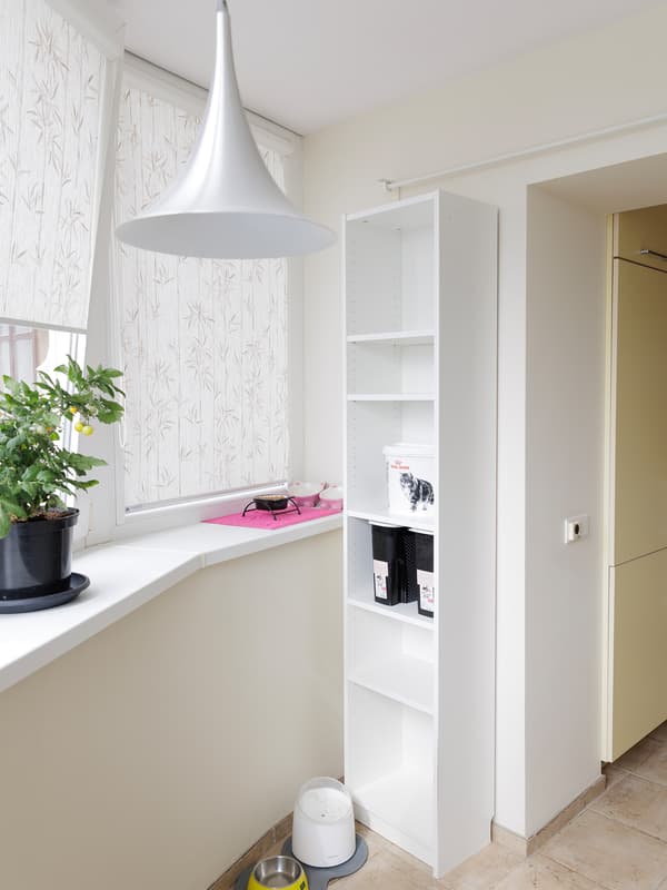 Narrow space with white walls, a white door, and some shelves on the right.