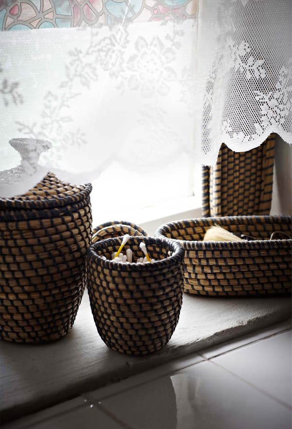 Natural fibre, woven baskets sitting on a window sill, providing storage for small things. 