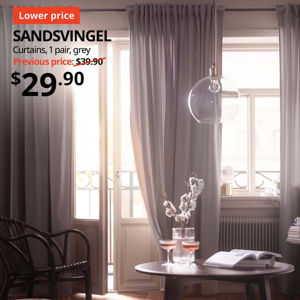 Natural light filtering through a bedroom through a pair of grey SANDSVINGEL curtains. Price: $29.90. Previous price: $39.90.