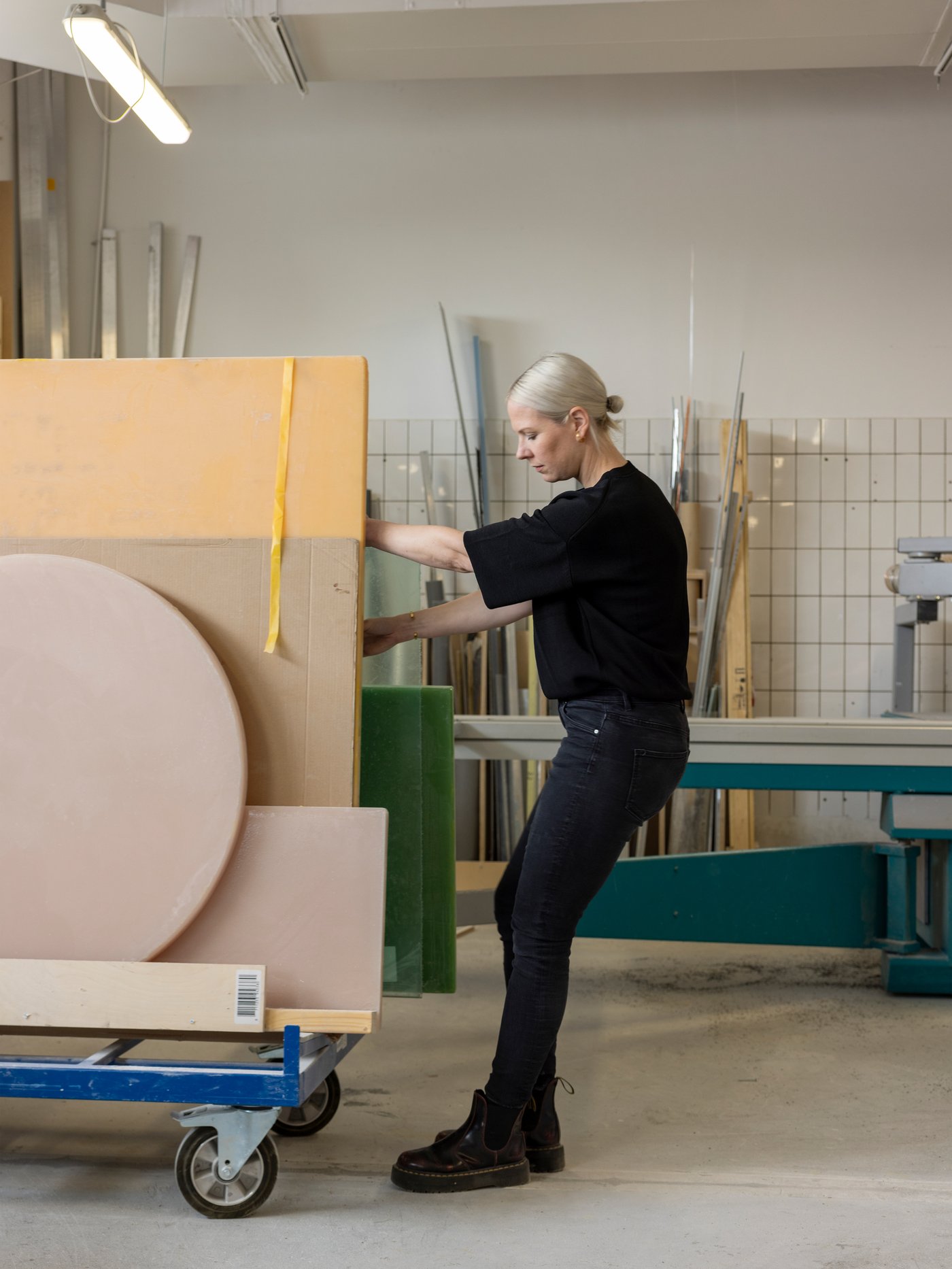 Návrhářka Sabine Marcelis, oblečená v černém, táhne ve rotterdamské dílně vozík s listy pryskyřice a lepenky.