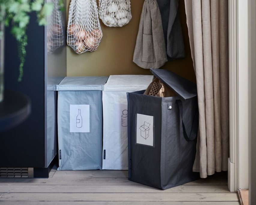 Neben einem schwarzen Schrank stehen 3 Taschen für Pfandflaschen Aufbewahrung