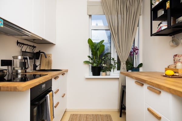 Небольшая линейная кухня с деревянной столешницей, встроенной техникой и окном.