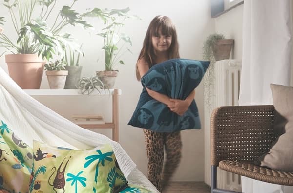 Nena xogando con coxíns no salón da casa.