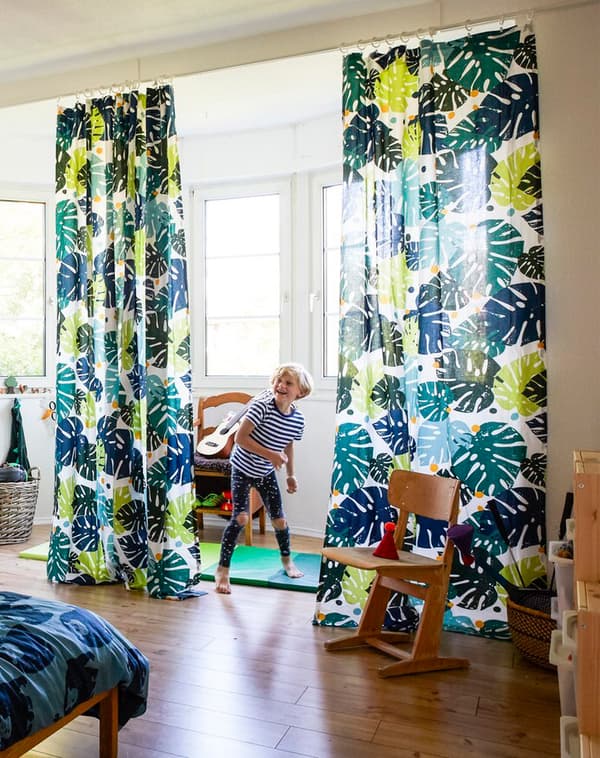 Neno xogando nun dormitorio grande con téxtiles con temática de xungla.