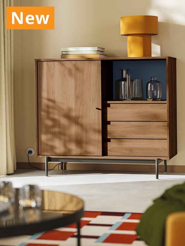 NEW IKEA product. A RÅDMANSÖ cabinet in brown walnut effect placed in modern Scandinavian living room setting with yellow STOCKHOLM 2025 table lamp on top of it.
