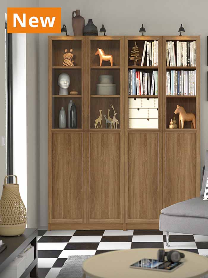 NEW IKEA product. Brown walnut effect BILLY bookcase with shelves and doors placed in a modern Scandinavian living room setting.