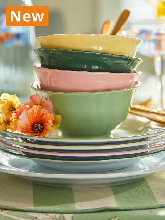 NEW IKEA product. Colourful UPPLAGA bowls stacked on four side plates in white/mixed colours on a green tablecloth on dining table.