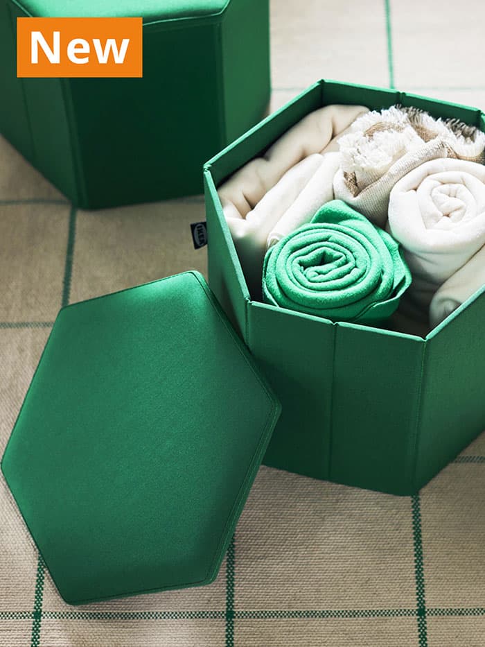 NEW IKEA product. Green KJUGE footstools filled with throws, used as storage in living room.