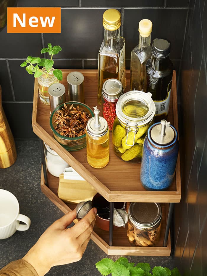 NEW IKEA product. Metal/bamboo NÅLBLECKA corner shelf, 28 cm, for kitchen countertop, filled with several kitchen sauces, bottles and jars.