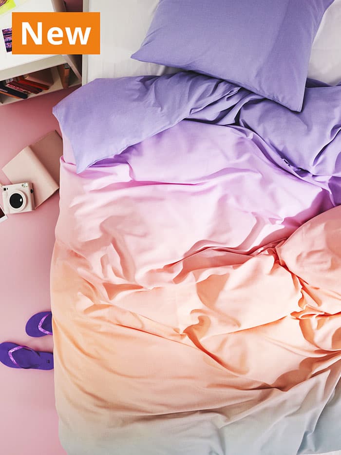 NEW IKEA product. Multicolour FLÄDERBUSKE duvet cover and pillowcase sprawled over bed.