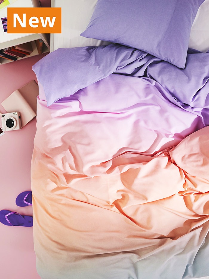 NEW IKEA product. Multicolour FLÄDERBUSKE duvet cover and pillowcase sprawled over bed.