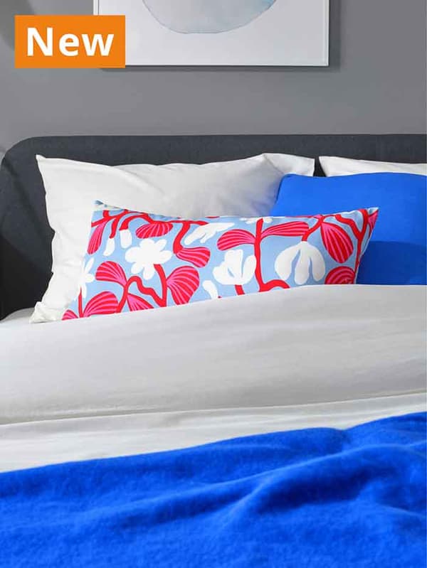 NEW IKEA product. SANDMOTT floral patterned cushion on a queen sized bed.