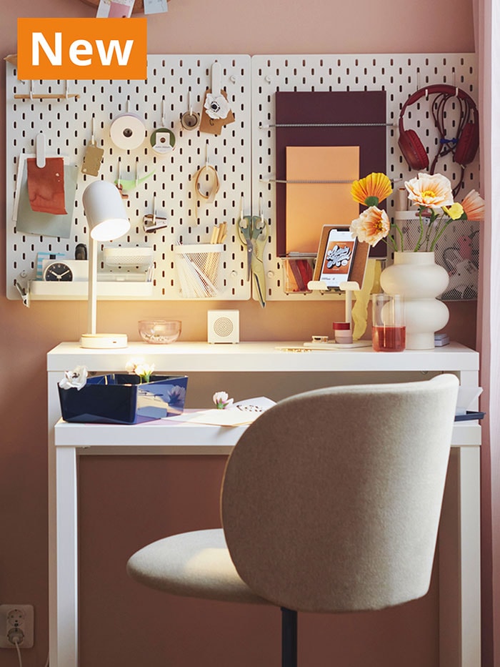 NEW IKEA product. White LÄNGDHOPP pull-out desk in a study room facing white SKADIS pegboard and white ENSMARKE lamp. KRYLBO swivel chair is tucked into the desk.