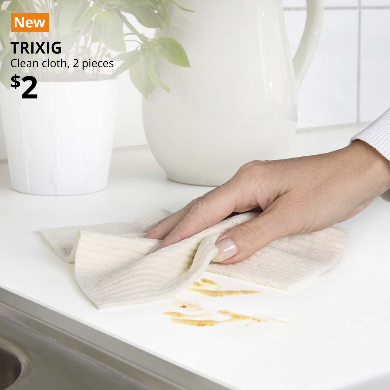 NEW tag. A hand using a white TRIXIG cleaning cloth to wipe away stains on the kitchen counter. Price: $2.