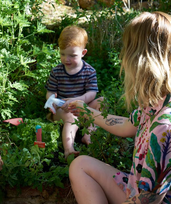 Nici își ajută fiul să ude plantele cu o sticlă cu pulverizator.