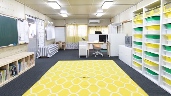 床には黄色のラグで明るい印象に。また棚の中にボックスを使用し整理整頓された収納棚。