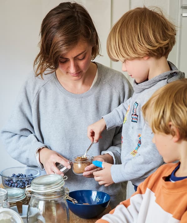 Nina e os seus dous fillos preparando o almorzo xuntos na cociña.
