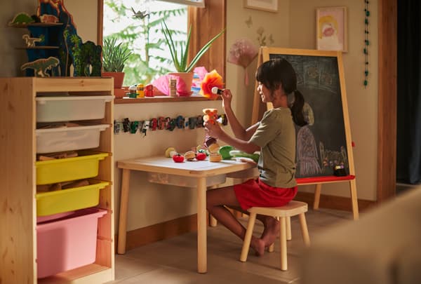 Niña sentada en su escritorio de madera y haciendo cosas con arte.