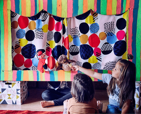 Niños jugando con un teatro de marionetas de cartón