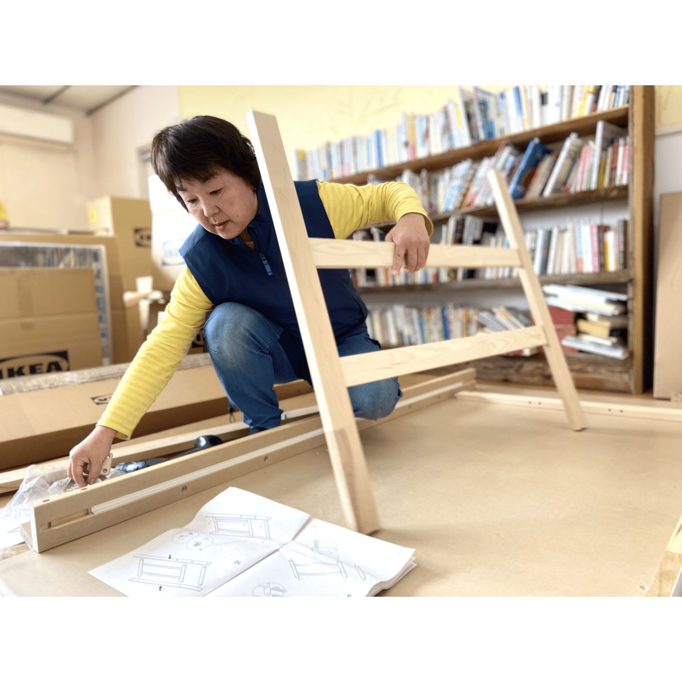 床にしゃがんで木製のフレームを組み立てている人