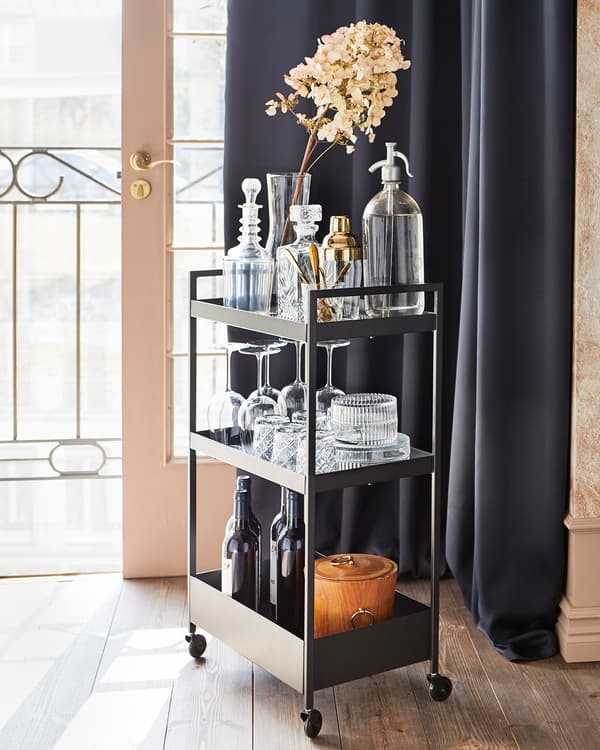 NISSAFORS trolley in black with castors, holding a soda syphon, various glasses, some bottles and a plant in a glass vase.