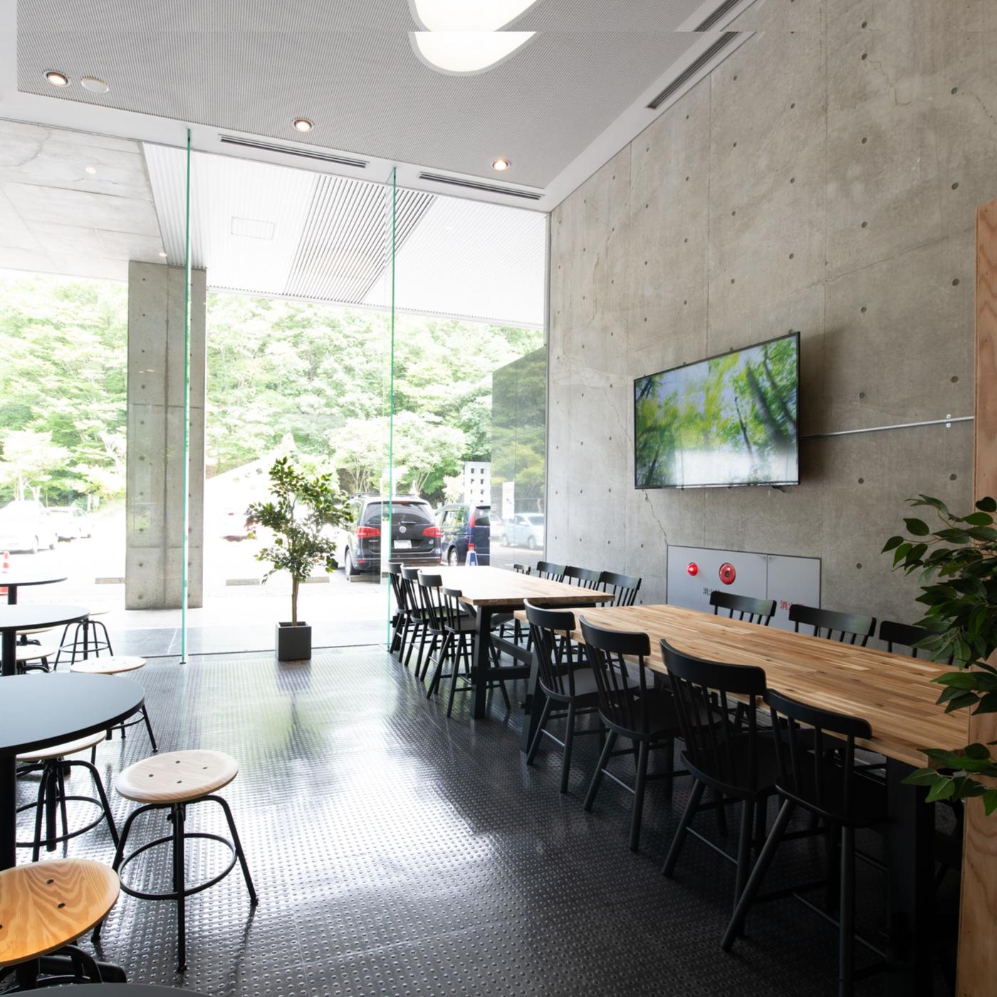 壁際にテーブルとチェアが並んでいるカフェ