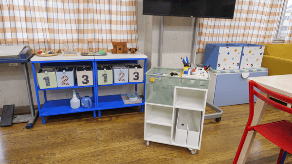 数字の収納ボックスが並んでいる棚や机やいすなどがある部屋