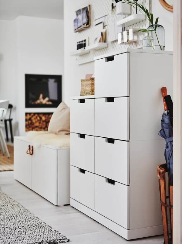 ตู้ลิ้นชัก NORDLI/นูร์ดลี สีขาวตั้งอยู่ตรงผนังสีขาวใกล้กับโถงทางเดินที่ตกแต่งแบบเปิดโล่งไม่มีการกั้นห้อง