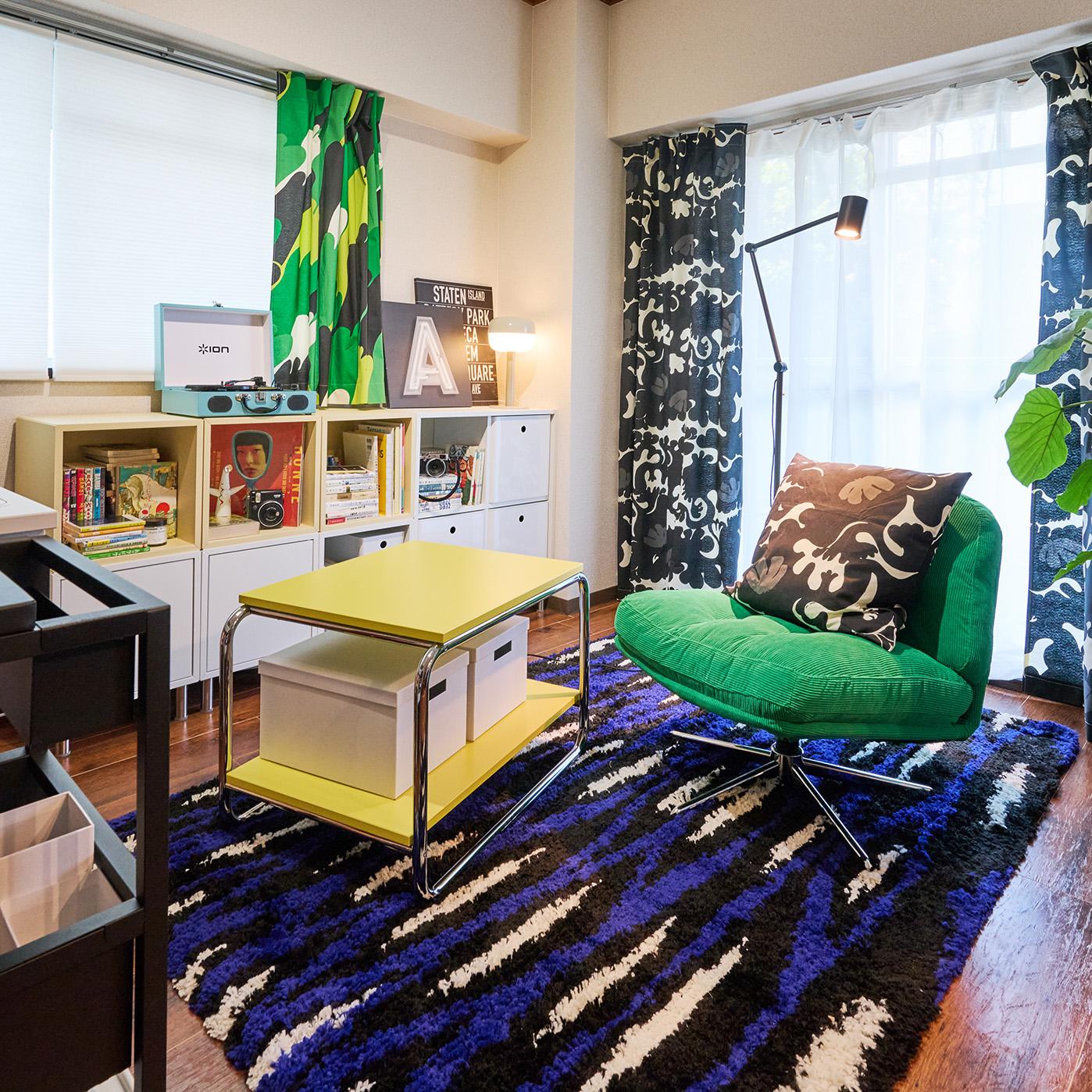 緑の回転椅子と黄色のコーヒーテーブル、本棚がある居心地の良いリビング。