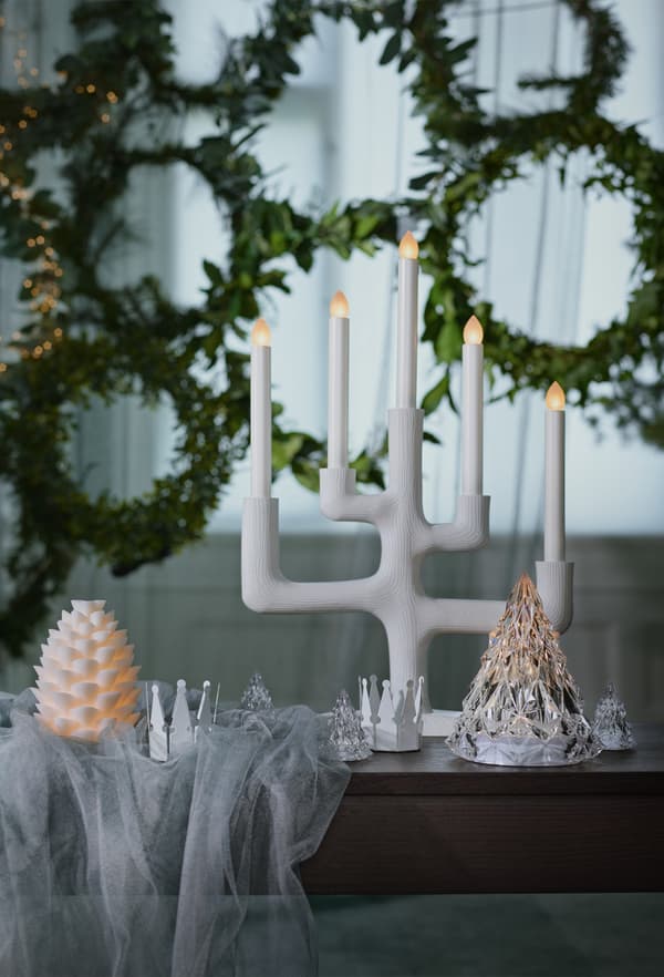 Nouveau chandelier blanc IKEA STRÅLA posé sur une table, devant des couronnes festives.