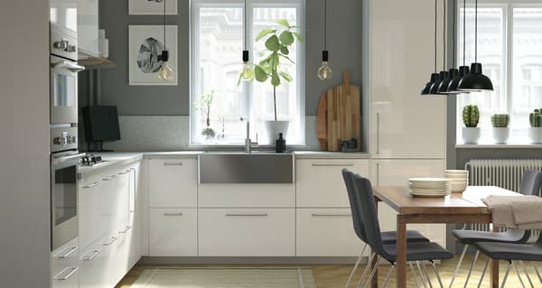 Nowoczesna, jasna kuchnia IKEA METOD z białymi drzwiami i szufladami RINGHULT, zlewem ze stali nierdzewnej i otwartą przestrzenią.