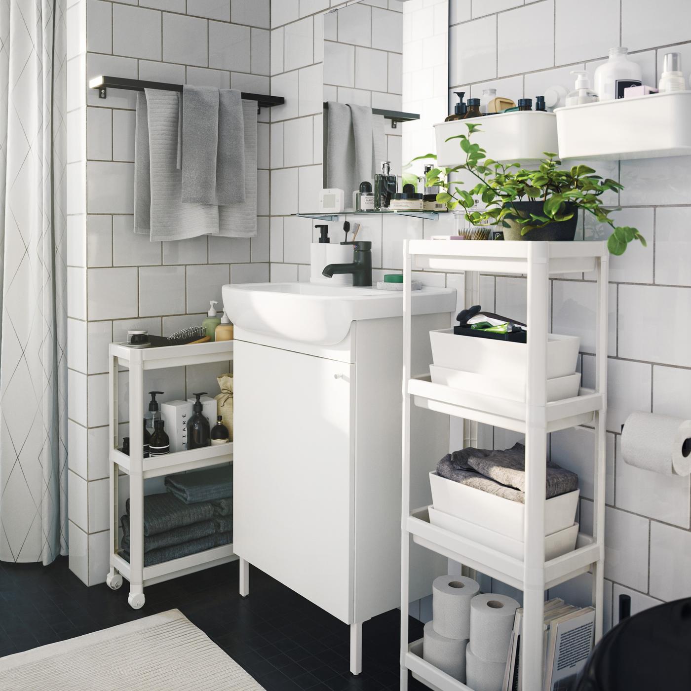 Nowoczesna łazienka, w której dominuje jeden kolor, kilka mebli do przechowywania i oszczędzających miejsce pojemników oraz zielone rośliny domowe.